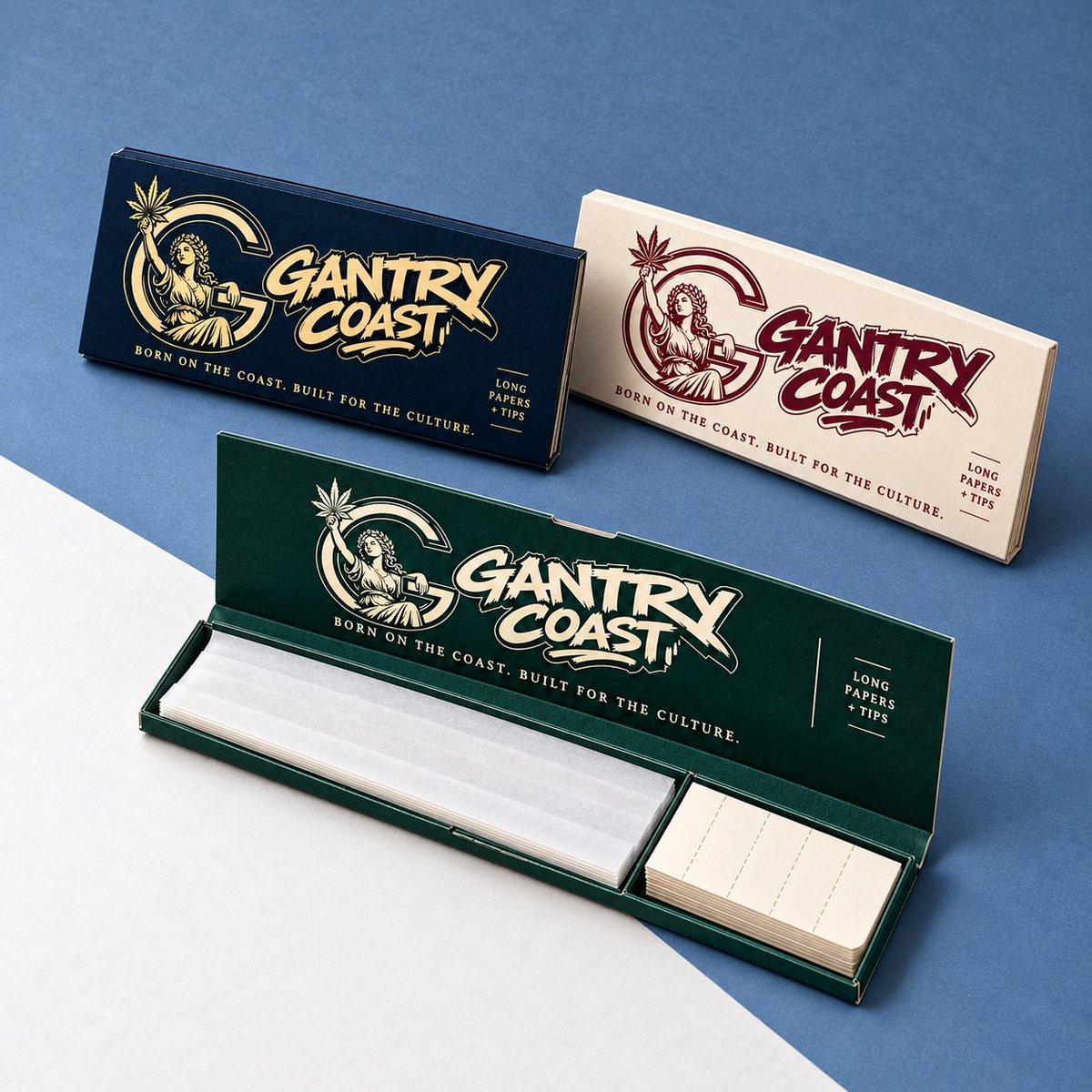 Three Gantry Coast branded rolling papers boxes in navy, cream, and green colors displayed on a two-tone blue and white background