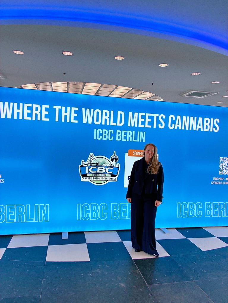 Woman in dark blazer standing in front of ICBC Berlin blue banner that reads Where the World Meets Cannabis at indoor venue